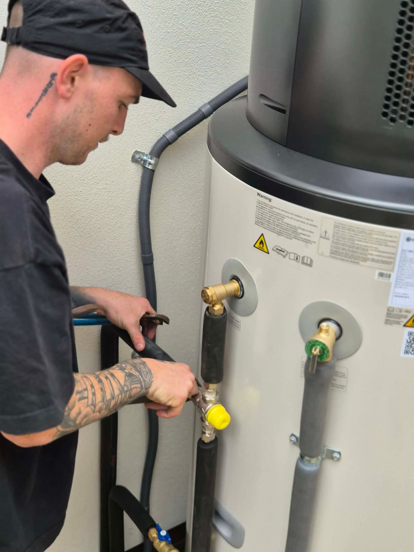 DARK plumber servicing a hot water system on the Gold Coast